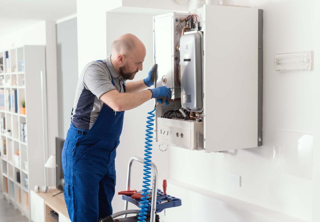 Technician performing home boiler repair in a residential basement.